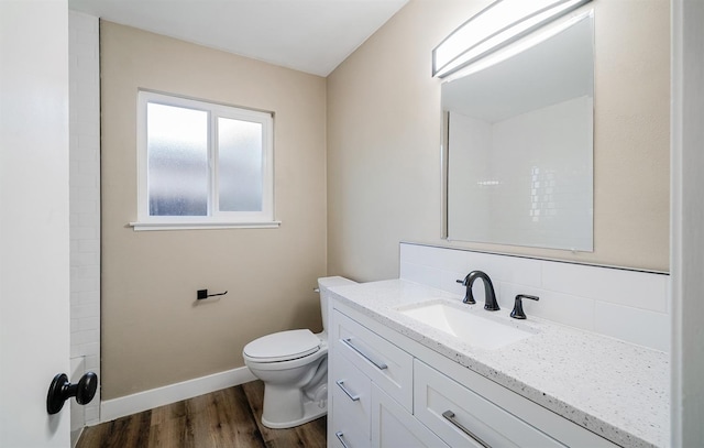 bathroom with baseboards, decorative backsplash, toilet, wood finished floors, and vanity