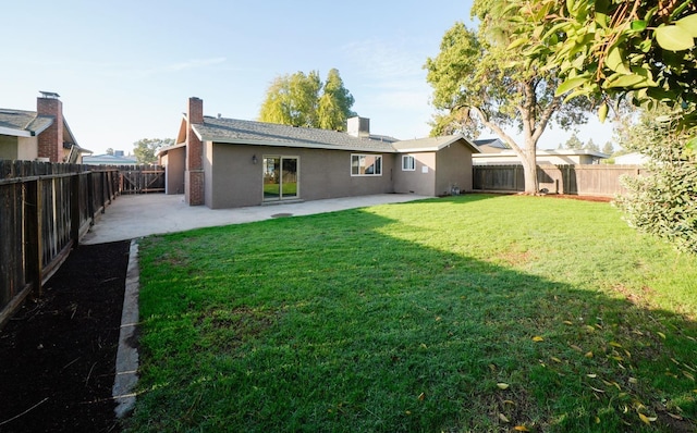 back of property with a fenced backyard, a lawn, and a patio