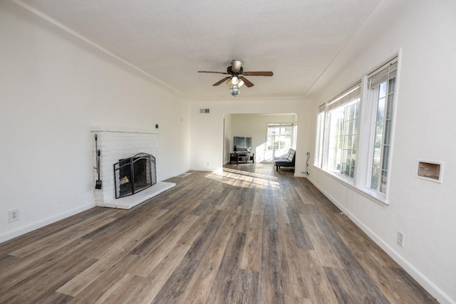 unfurnished living room featuring a brick fireplace, dark wood-type flooring, and ceiling fan