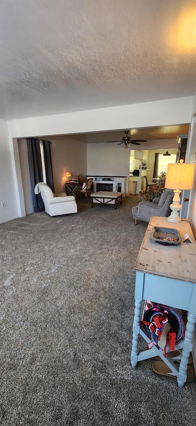 living room with ceiling fan, carpet flooring, and a textured ceiling