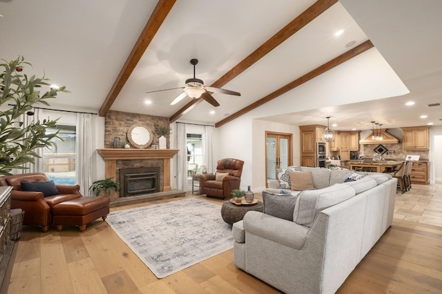 living room with lofted ceiling with beams, a stone fireplace, ceiling fan, and light hardwood / wood-style flooring