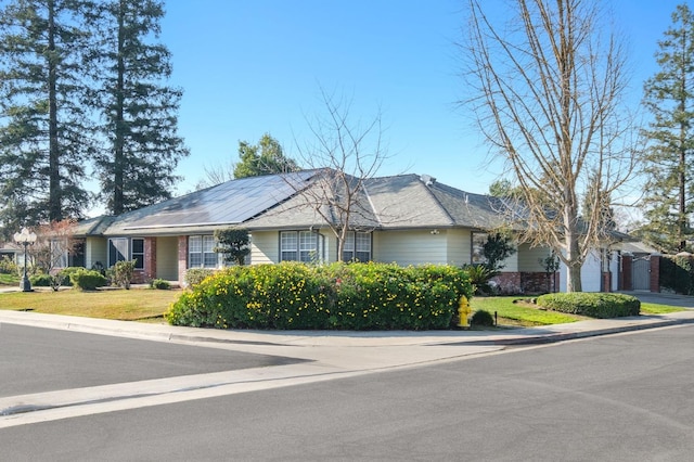 single story home featuring a garage, a front yard, and solar panels