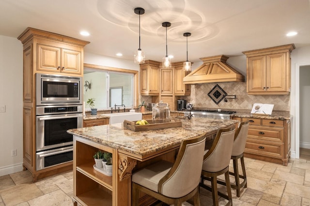 kitchen featuring sink, appliances with stainless steel finishes, light stone countertops, a kitchen island, and custom exhaust hood