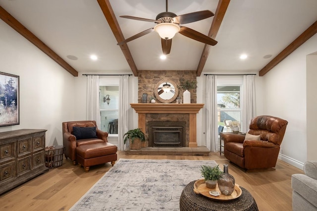 sitting room featuring beamed ceiling, ceiling fan, a fireplace, and light hardwood / wood-style flooring