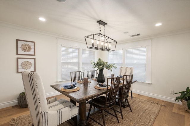 dining area with crown molding, a chandelier, and hardwood / wood-style floors