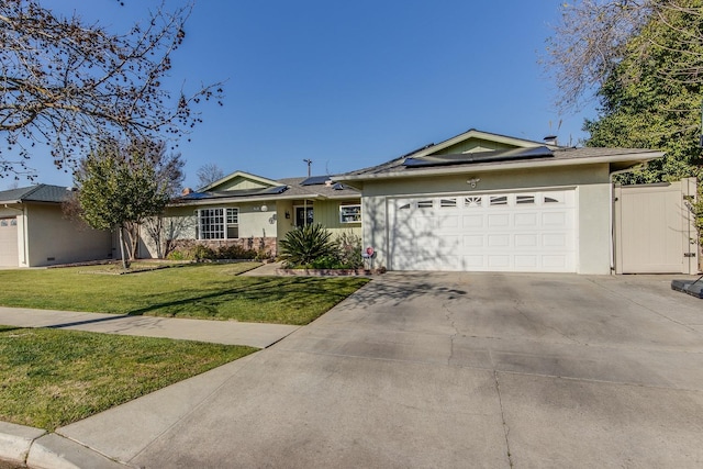 ranch-style house featuring a garage, concrete driveway, a gate, roof mounted solar panels, and a front yard