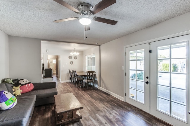 living area featuring a textured ceiling, ceiling fan with notable chandelier, wood finished floors, baseboards, and french doors