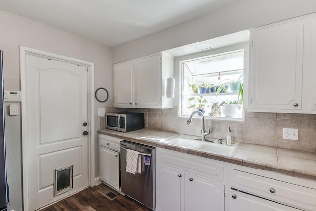 kitchen with appliances with stainless steel finishes, white cabinetry, a sink, and tasteful backsplash