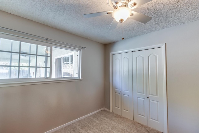 unfurnished bedroom with baseboards, a ceiling fan, carpet, a textured ceiling, and a closet