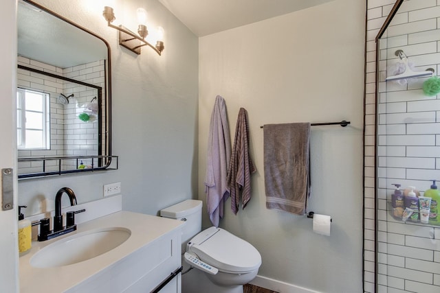 bathroom featuring toilet, a tile shower, and vanity