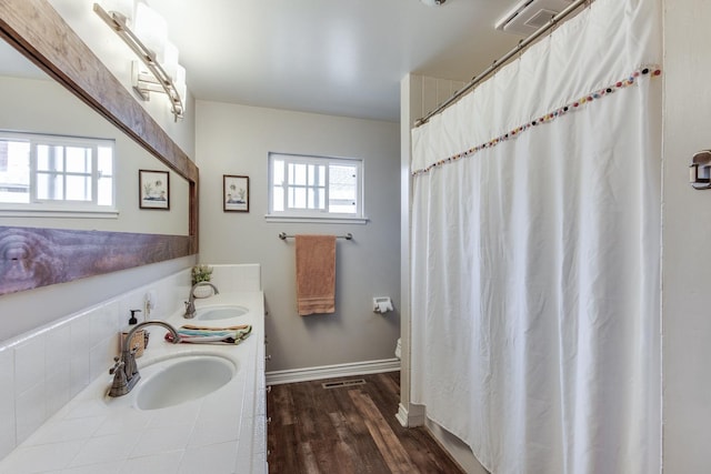 full bath with double vanity, wood finished floors, a sink, and visible vents