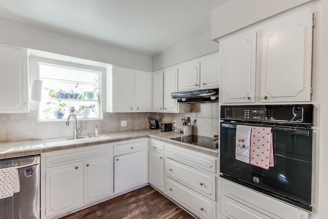 kitchen with under cabinet range hood, a sink, white cabinetry, black appliances, and tasteful backsplash