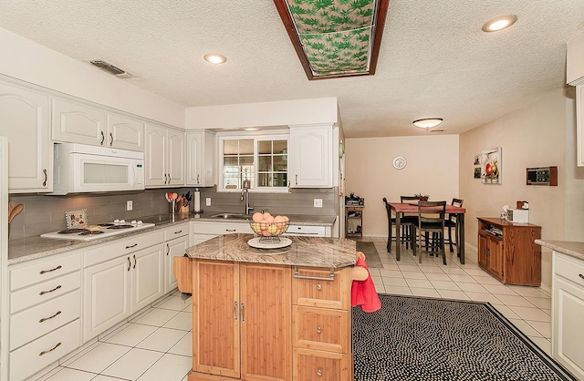 kitchen with white cabinetry, light tile patterned floors, white appliances, and a kitchen island