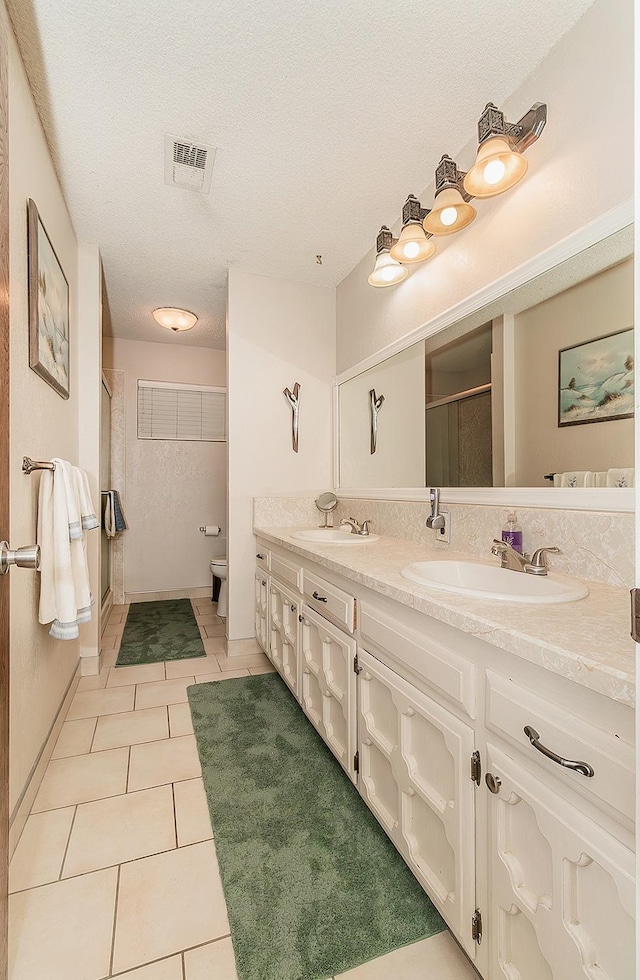 bathroom featuring tile patterned flooring, vanity, an enclosed shower, toilet, and a textured ceiling