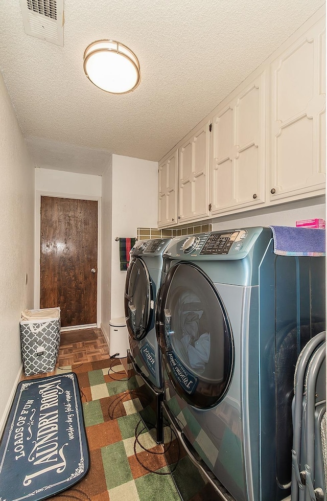 laundry room with cabinets, dark parquet flooring, separate washer and dryer, and a textured ceiling