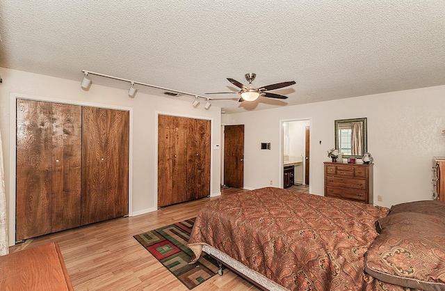 bedroom featuring two closets, a textured ceiling, ceiling fan, and ensuite bathroom