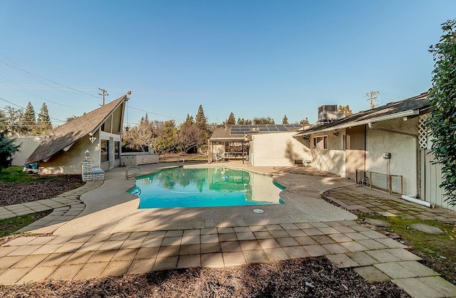 view of swimming pool featuring an outbuilding, central AC unit, and a patio area