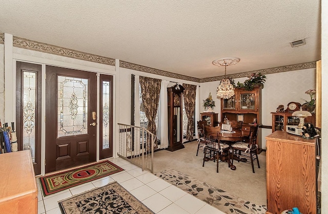 tiled entrance foyer featuring a notable chandelier and a textured ceiling