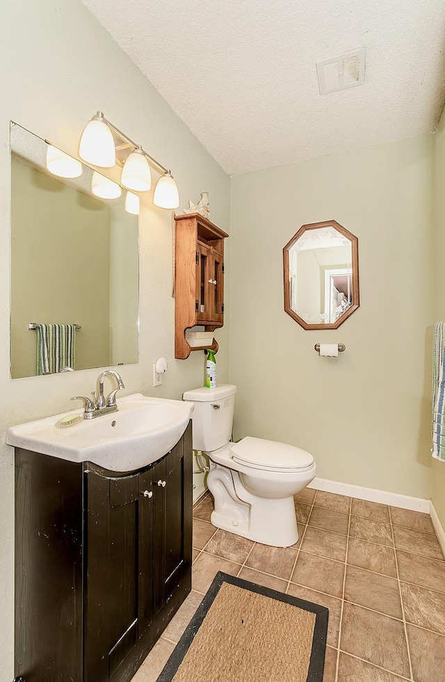 bathroom featuring tile patterned flooring, vanity, a textured ceiling, and toilet