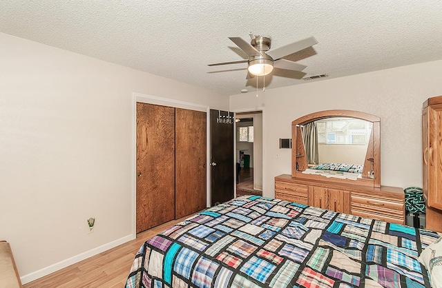 bedroom with ceiling fan, light hardwood / wood-style floors, a closet, and a textured ceiling