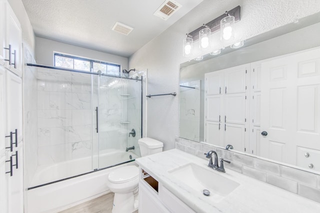 full bathroom featuring toilet, combined bath / shower with glass door, a textured ceiling, vanity, and hardwood / wood-style flooring