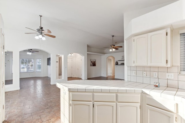 kitchen featuring vaulted ceiling, tile counters, ceiling fan, and decorative backsplash