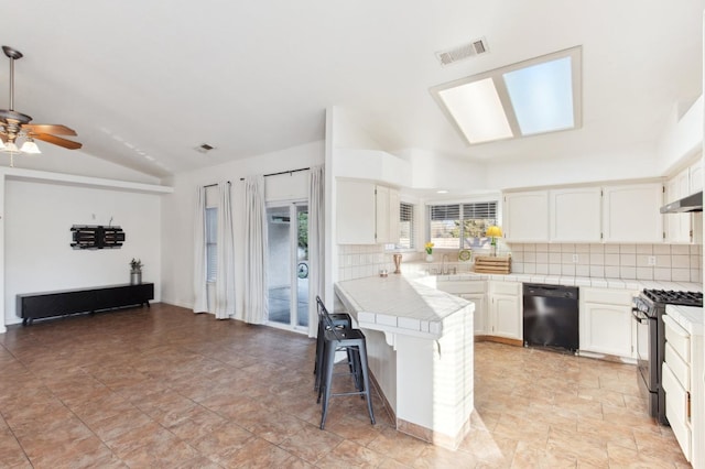 kitchen featuring black dishwasher, white cabinets, a kitchen breakfast bar, tile counters, and stainless steel gas range oven