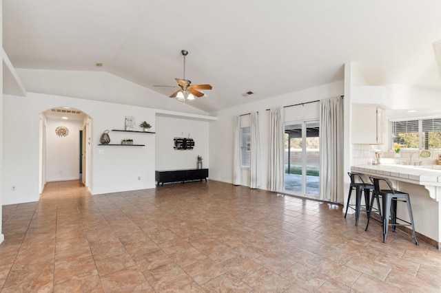 living room with ceiling fan, vaulted ceiling, sink, and a healthy amount of sunlight