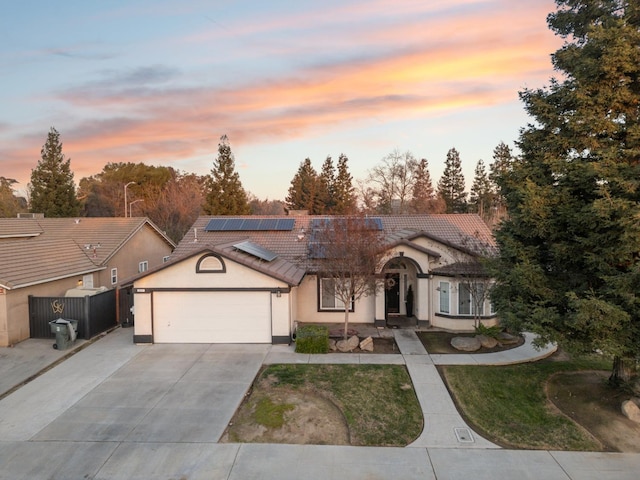 ranch-style house featuring a garage and solar panels