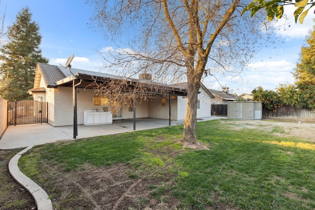 rear view of property featuring a storage unit, a patio, and a lawn