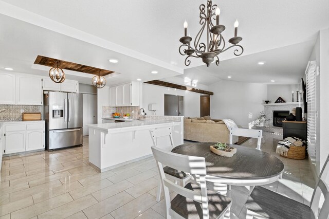 tiled dining space featuring a chandelier, sink, and a brick fireplace