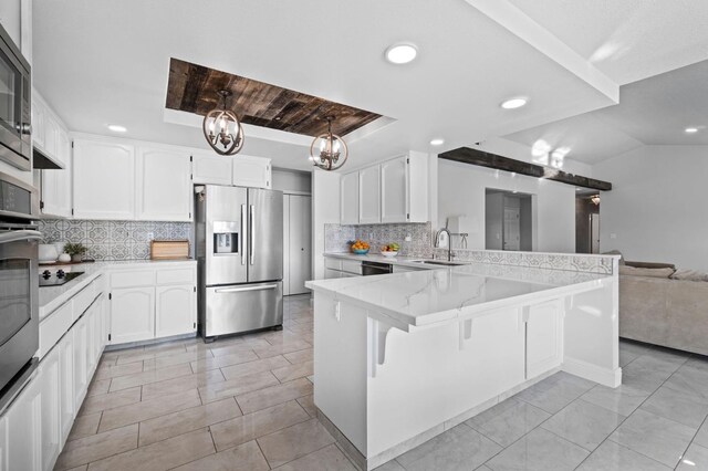 kitchen with white cabinetry, backsplash, a kitchen breakfast bar, black appliances, and kitchen peninsula