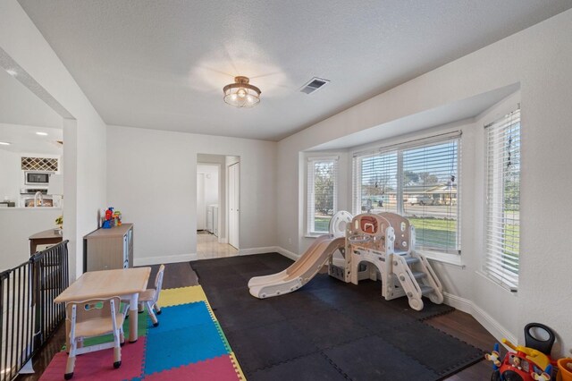 game room featuring wood-type flooring and a textured ceiling