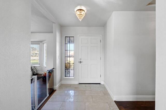 foyer entrance with a textured ceiling and light tile patterned floors