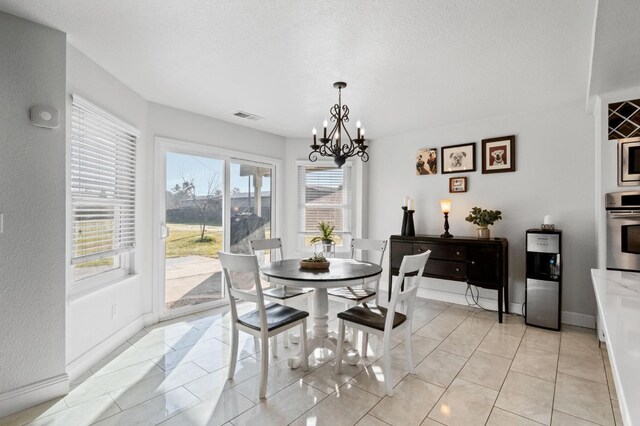 dining area with light tile patterned floors, a notable chandelier, and a textured ceiling