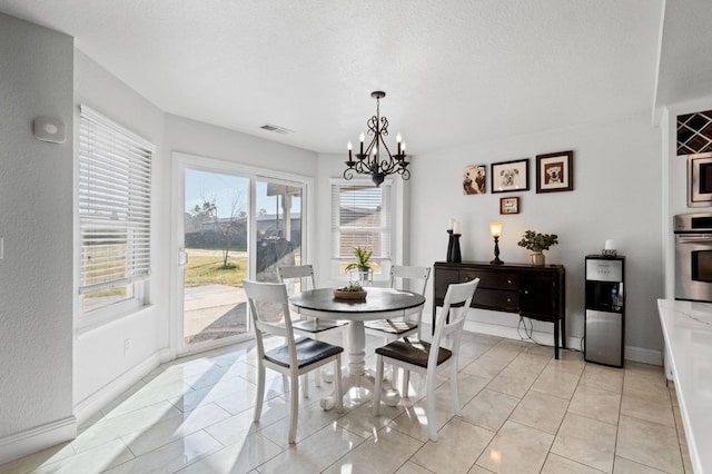 dining room with visible vents, a textured ceiling, an inviting chandelier, light tile patterned flooring, and baseboards