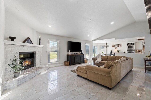 tiled living room featuring lofted ceiling, plenty of natural light, an inviting chandelier, and a fireplace