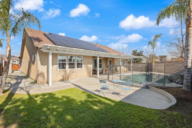 back of house featuring a fenced in pool, a patio area, solar panels, and a lawn