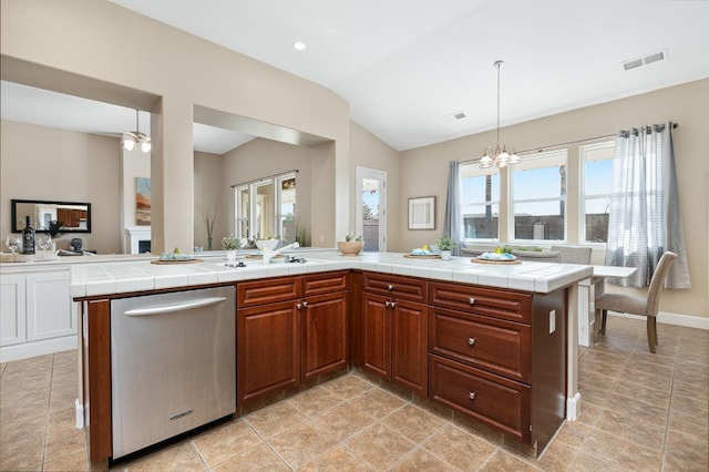 kitchen with stainless steel dishwasher, tile counters, hanging light fixtures, and a wealth of natural light