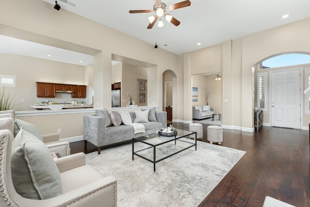 living room with ceiling fan, dark hardwood / wood-style floors, and a towering ceiling