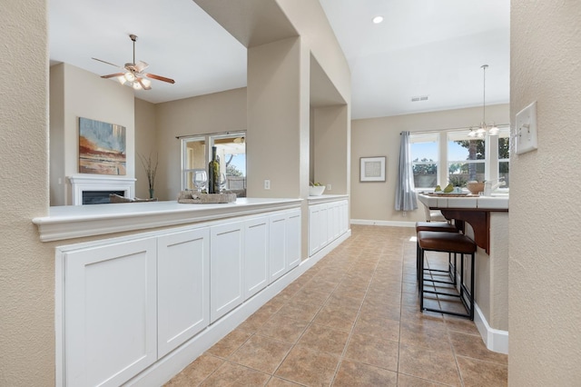 kitchen with white cabinetry, lofted ceiling, a healthy amount of sunlight, and light tile patterned floors