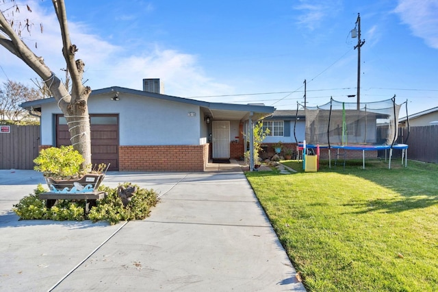 ranch-style home with a trampoline and a front lawn