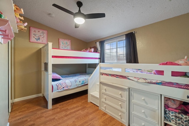 bedroom with vaulted ceiling, ceiling fan, a textured ceiling, and light wood-type flooring