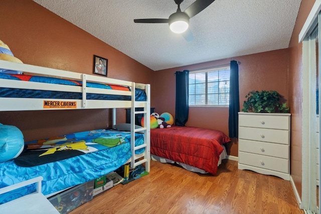 bedroom with lofted ceiling, ceiling fan, a textured ceiling, and light wood-type flooring