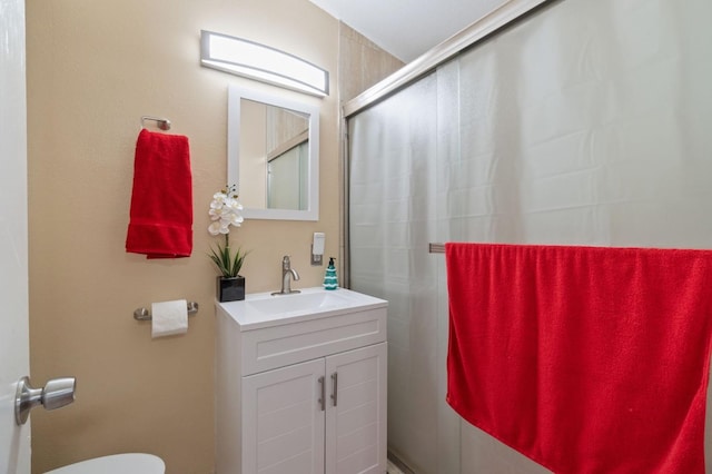 bathroom featuring vanity, a shower with door, and toilet