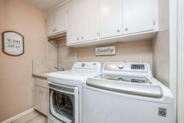 washroom featuring washing machine and clothes dryer, light tile patterned floors, cabinet space, a sink, and baseboards