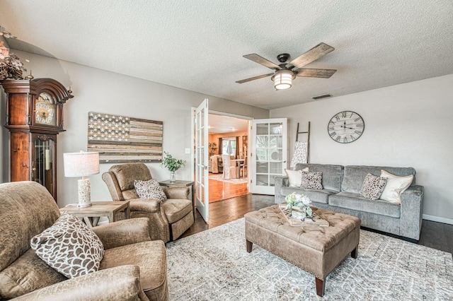 living area with french doors, visible vents, ceiling fan, a textured ceiling, and wood finished floors