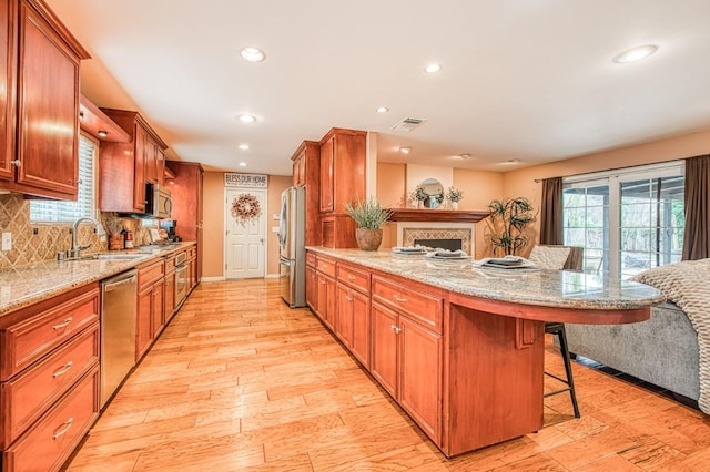 kitchen featuring appliances with stainless steel finishes, a breakfast bar, a peninsula, a sink, and backsplash