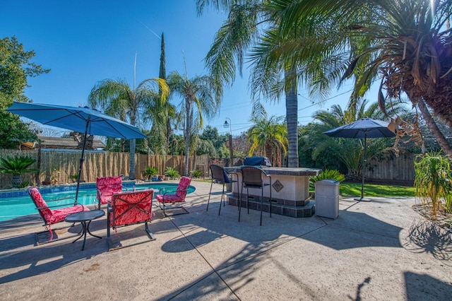 view of patio / terrace with outdoor dry bar, a fenced backyard, and a fenced in pool