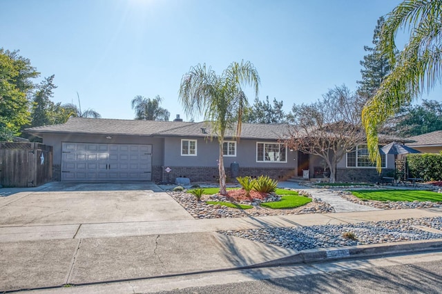 ranch-style house featuring brick siding, concrete driveway, an attached garage, fence, and stucco siding